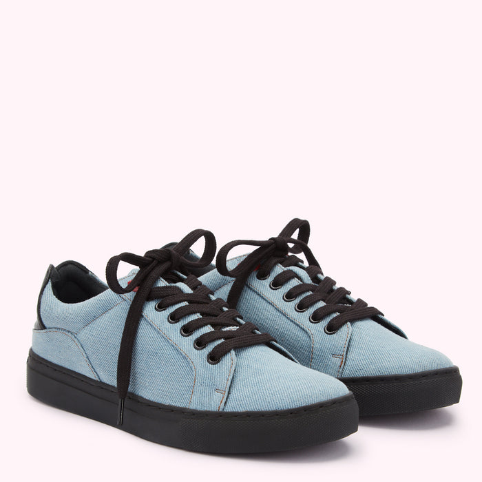 Pair of light blue denim low-top sneakers with black laces and soles against a white background.