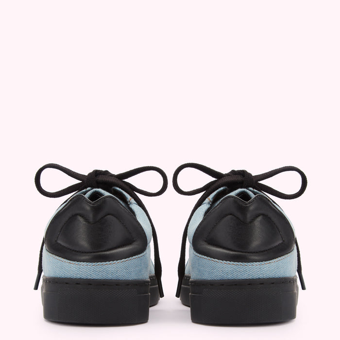 Pair of light blue denim sneakers with black laces and black leather accents on a white background.