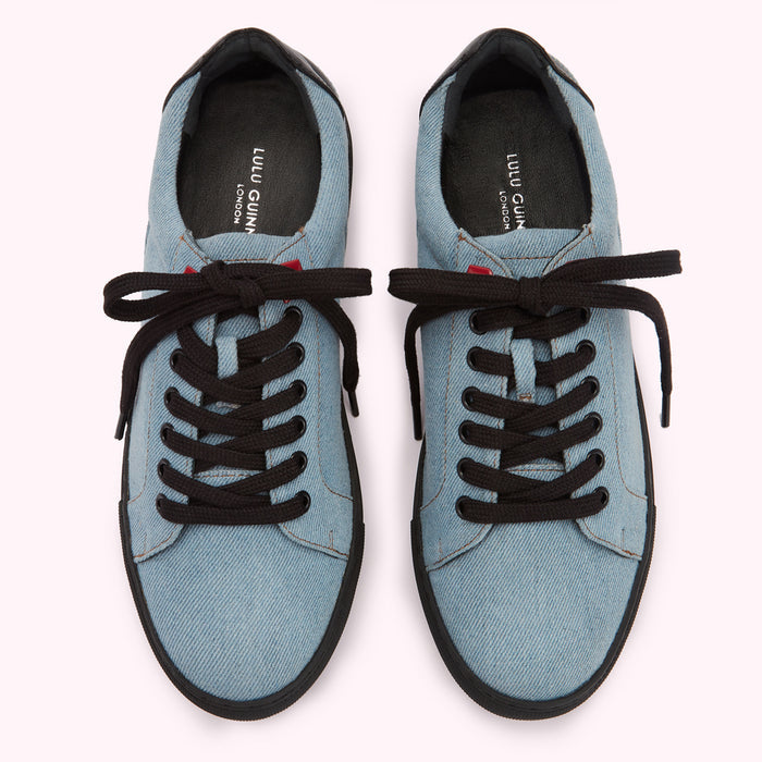 Pair of light blue denim Lulu Guinness London sneakers with black laces and trim, viewed from above on a white background.