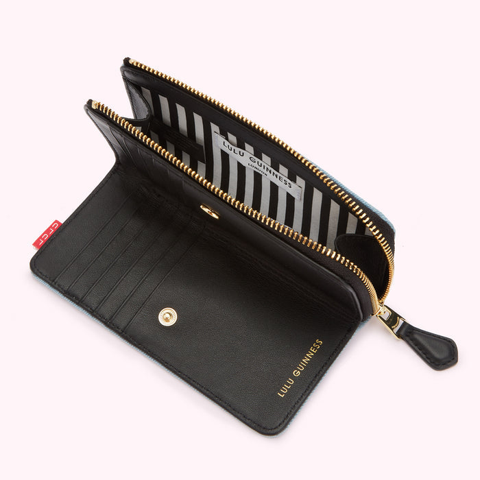 Open Lulu Guinness wallet in pale blue denim with black leather interior.