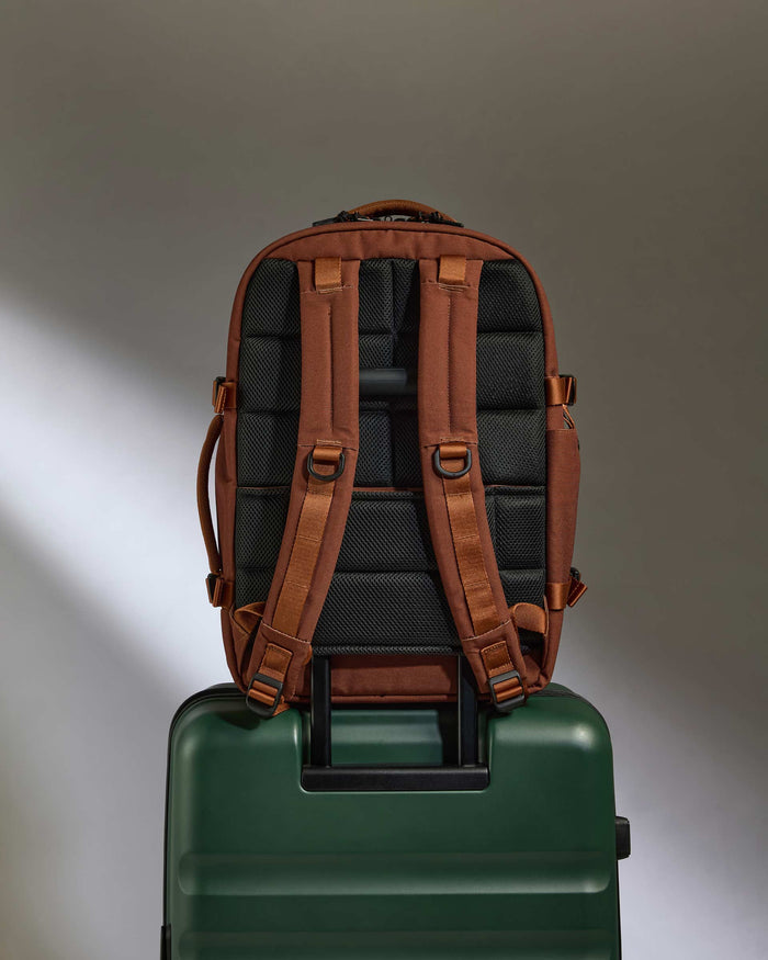 a backpack on top of a green suitcase
