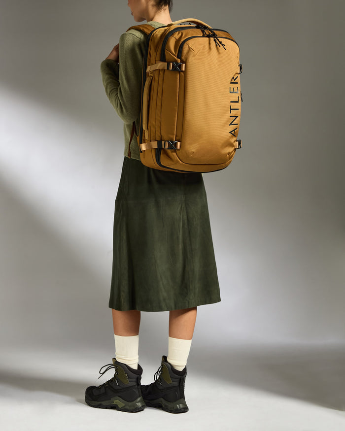 a woman wearing a green skirt and a green jacket with a large backpack