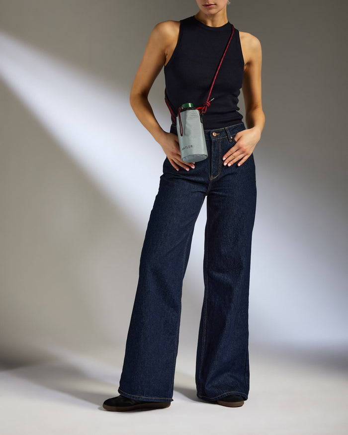 a woman in a black tank top and wide leg jeans
