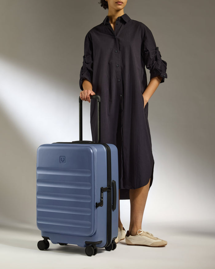 a woman in a black dress and sunglasses holding a suitcase