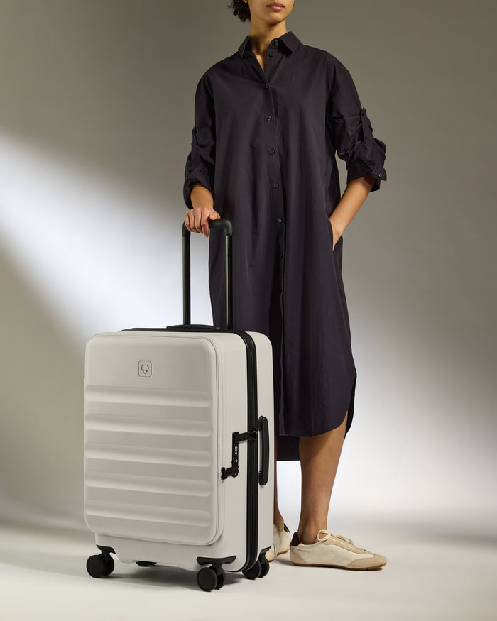 a woman in a black dress and white shoes holding a suitcase