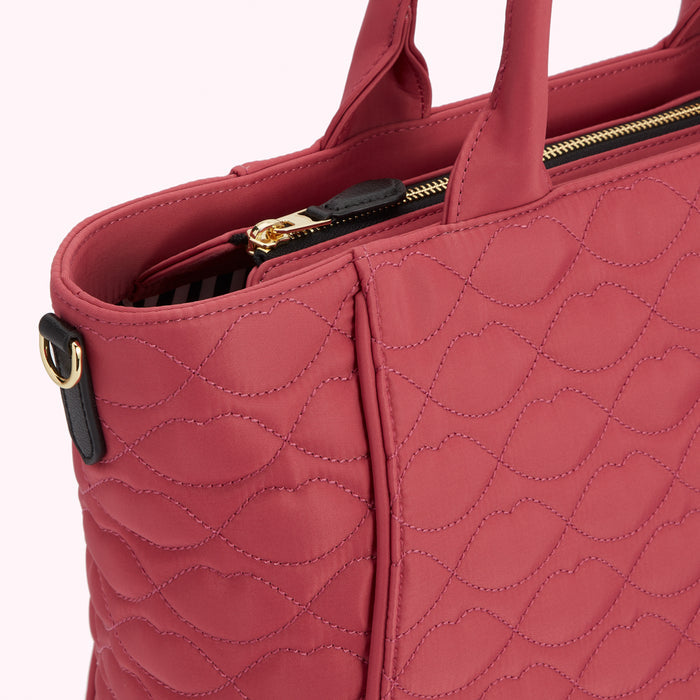 Close-up of a quilted pink tote bag with gold zipper.