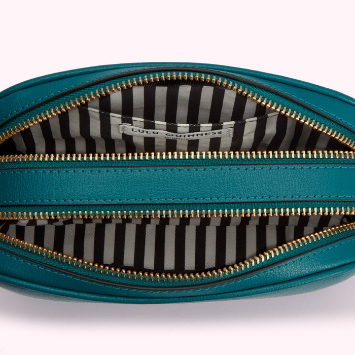 Inside of teal Lulu Guinness crossbody bag with gold zippers and black and white striped lining.