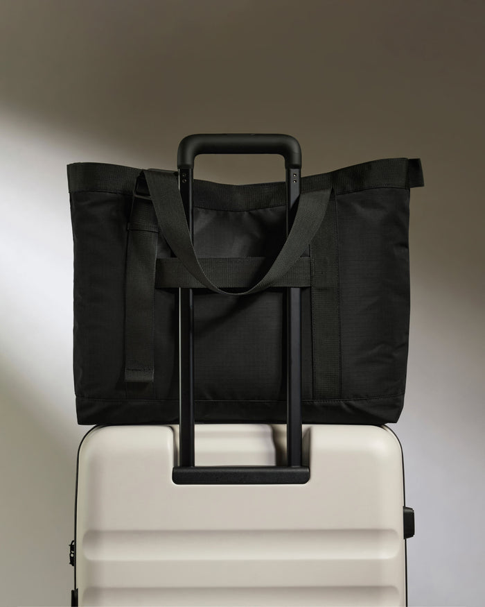 a black bag on top of a white suitcase