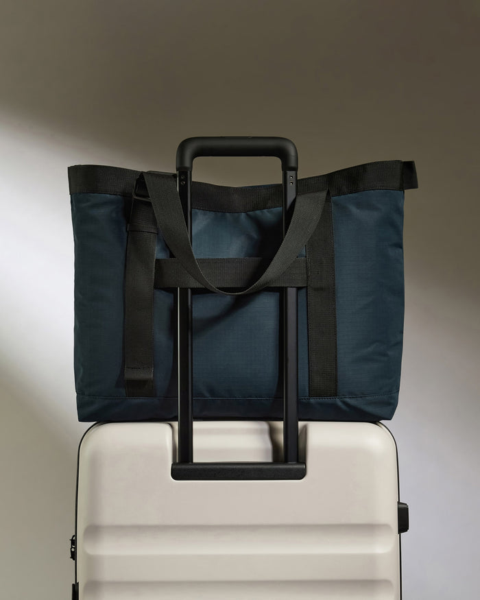 a blue bag on top of a white suitcase