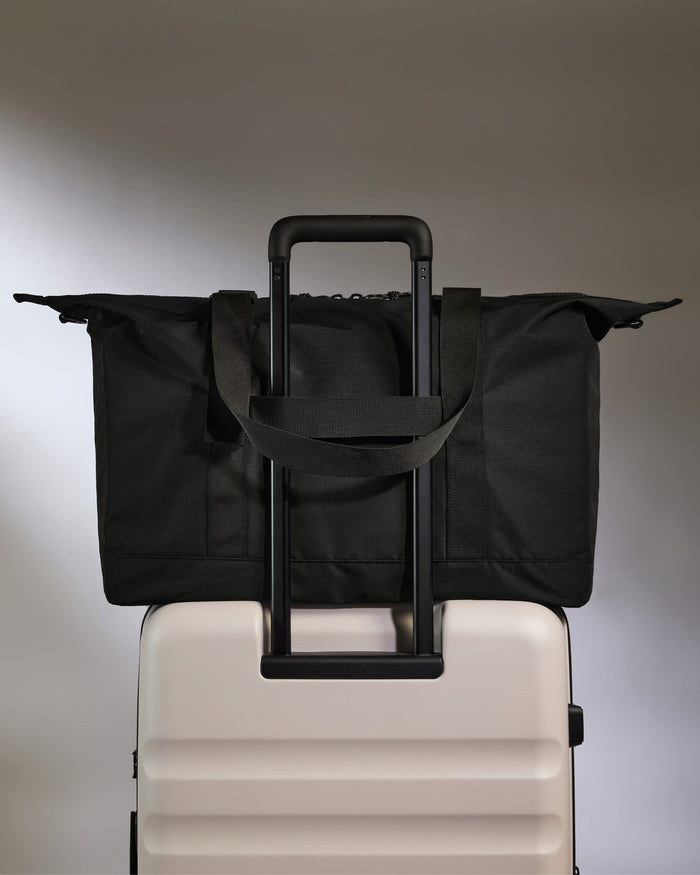 a black bag on top of a white suitcase