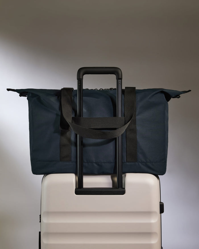 a blue bag on top of a white suitcase