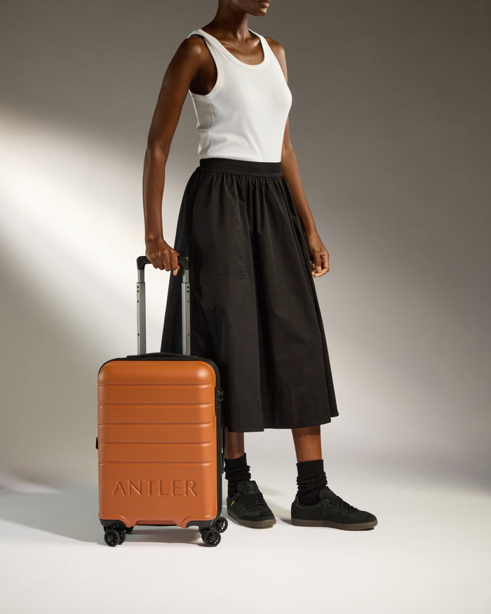 a woman in a white tank top and black skirt holding a suitcase