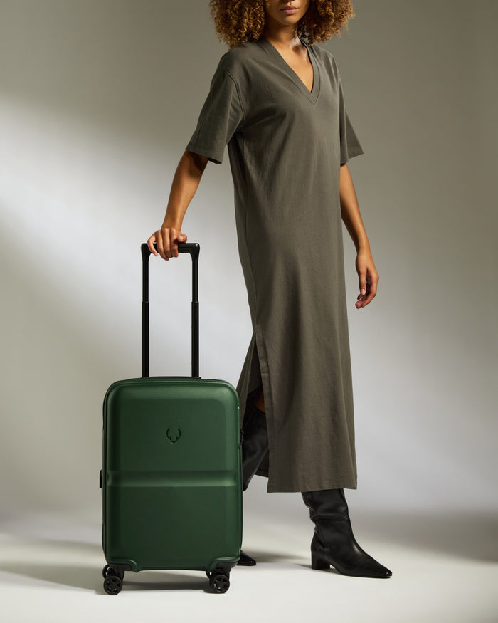 a woman in a long dress and boots holding a suitcase