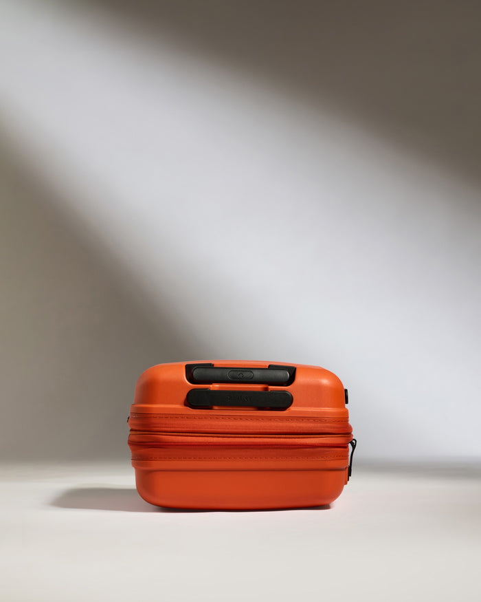 an orange suitcase on a white surface