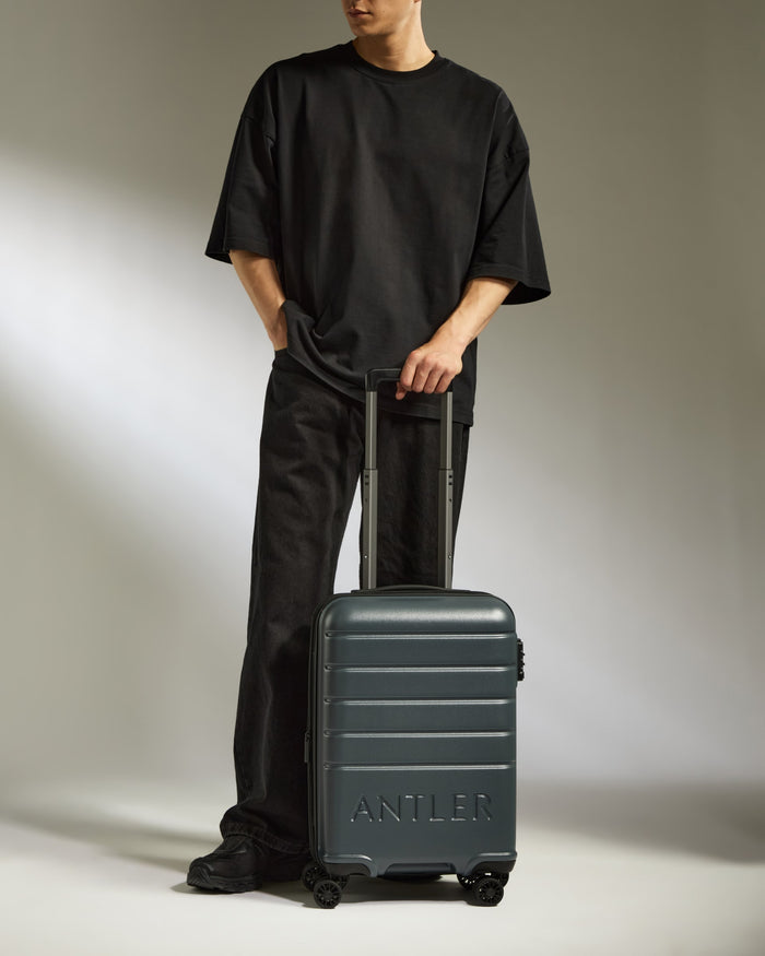 a man standing with his hands in his pockets and a suitcase