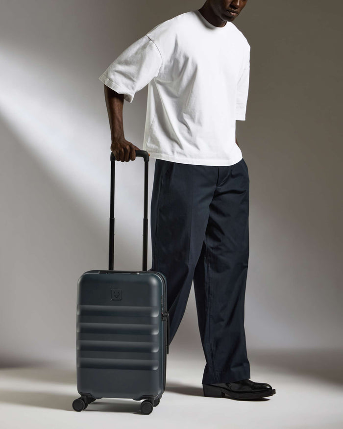 a man in a white shirt and black pants holding a suitcase