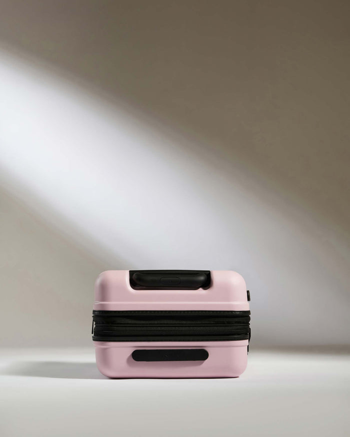 a pink suitcase with black straps