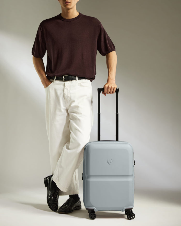 a man standing with his hand in his pocket and a suitcase