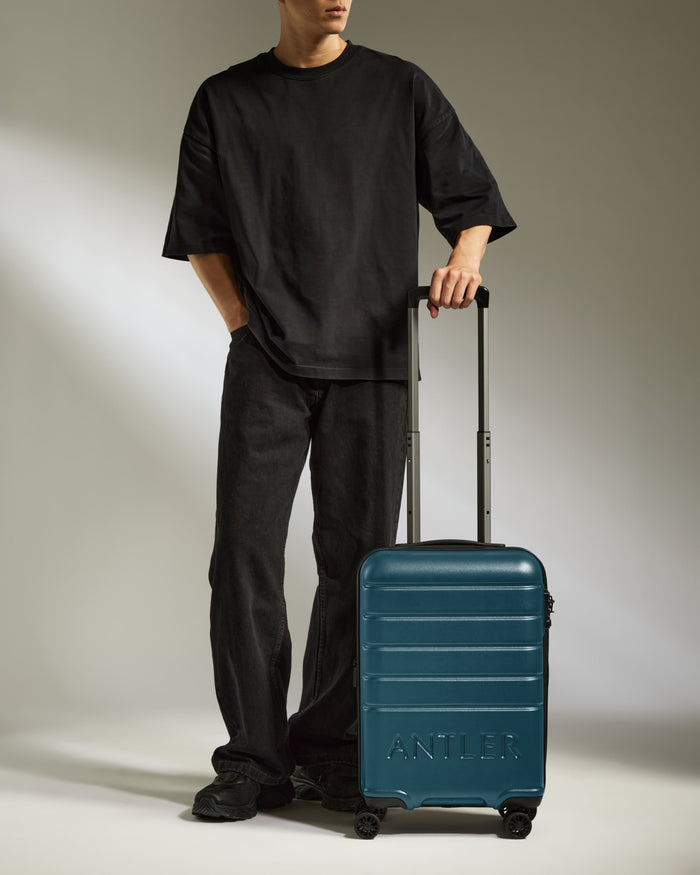 a man standing with his hands in his pockets and a suitcase
