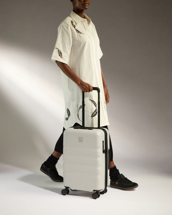 a woman in a white dress and black pants holding a suitcase