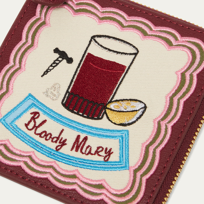 Embroidered design of a Bloody Mary cocktail on a wallet with text and graphics.