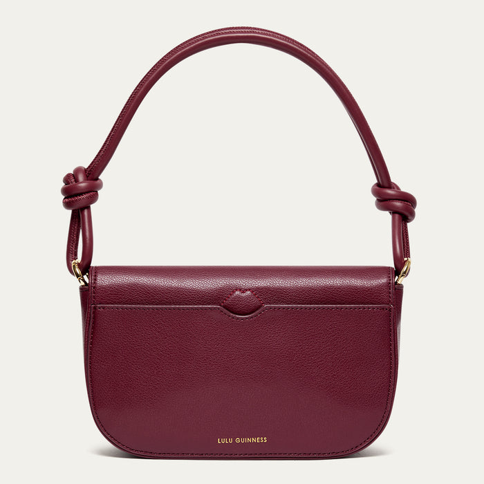 Back image of a burgundy leather shoulder bag with knotted handle and gold printed 'Lulu Guinness' logo on a light beige background