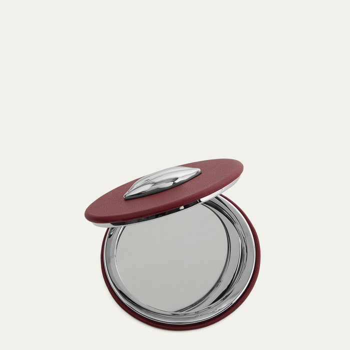 Compact mirror with a red lid on a white background