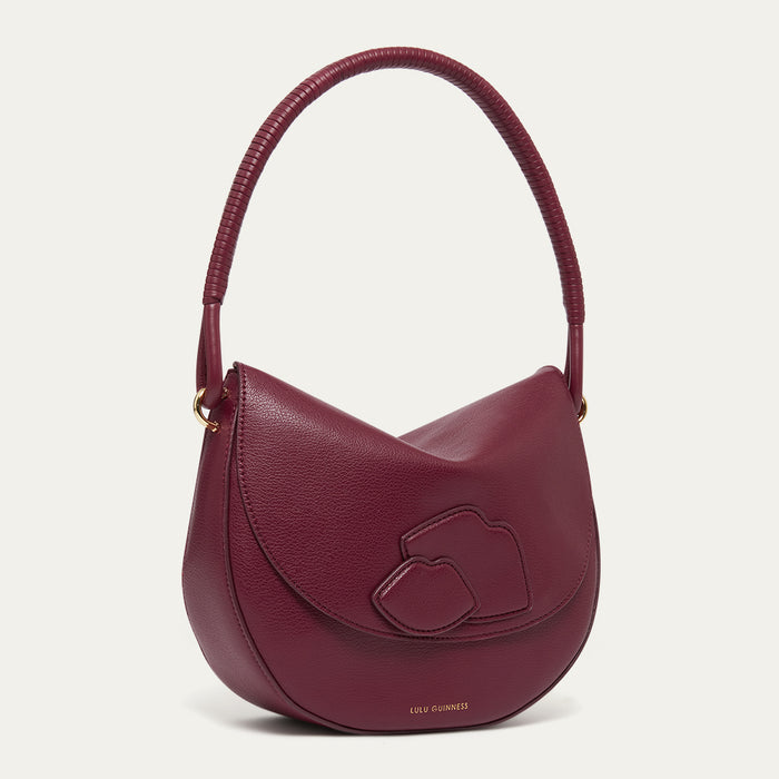 Burgundy leather shoulder bag with a corded handle and lip details on a light grey background