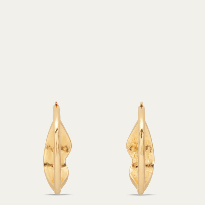 A pair of gold hoop earrings with a textured, organic lip design, displayed against a solid off-white background.