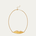 A gold necklace featuring a textured, sculptural lip-shaped pendant suspended from a delicate gold chain, set against a solid off-white background.