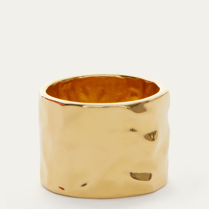 A wide, textured gold ring with a hammered, organic surface finish and a polished gold interior, shown on a clean white background.
