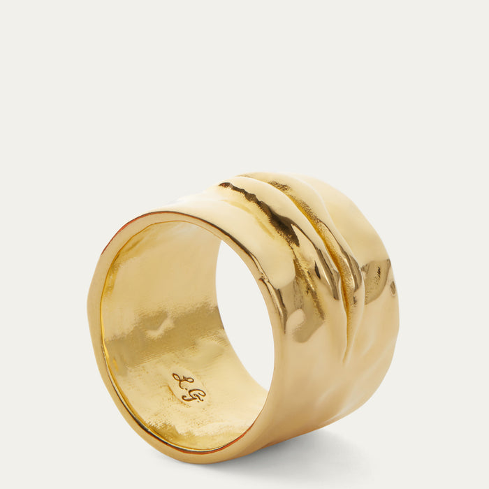 A wide, chunky gold ring with a textured, ridged exterior and a polished interior, shown on a light gray background.