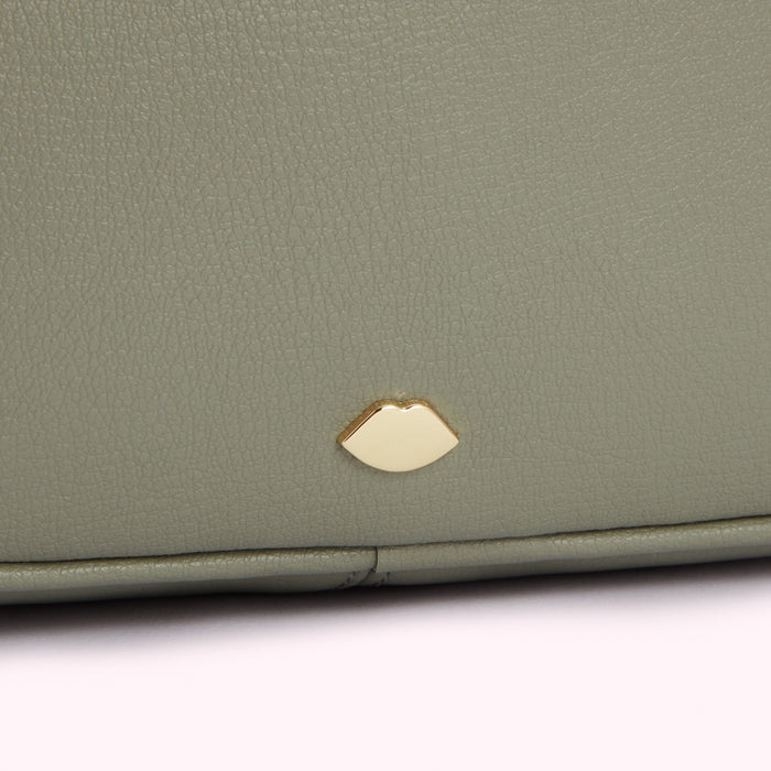 Close-up of a sage green textured handbag with a gold lip-shaped logo.