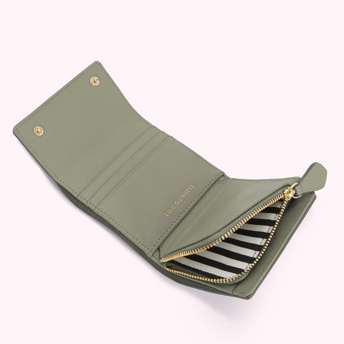 Sage green Lulu Guinness zip-around wallet open to reveal black and white striped interior.