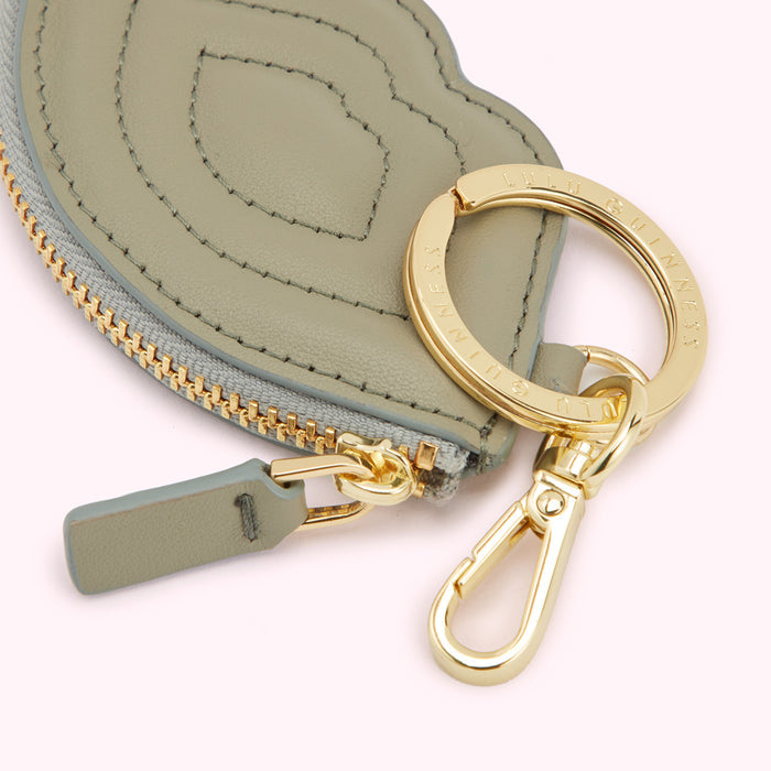 Close-up of a sage green Lulu Guinness coin purse with gold zipper and keyring.