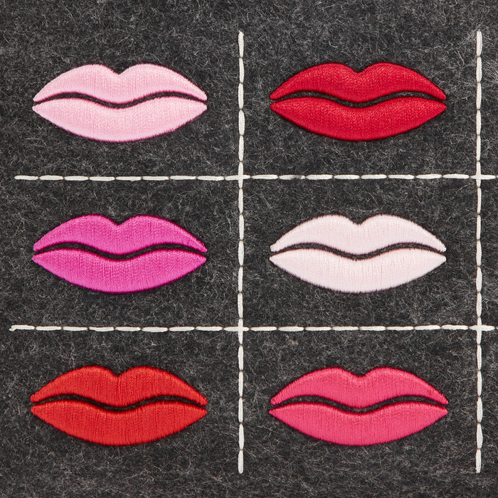 Six embroidered lips in varying shades of pink and red on a dark grey background.