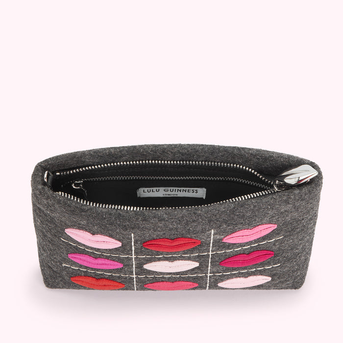 Overhead view of a grey felt Lulu Guinness pouch with embroidered lips in various shades of pink and red.