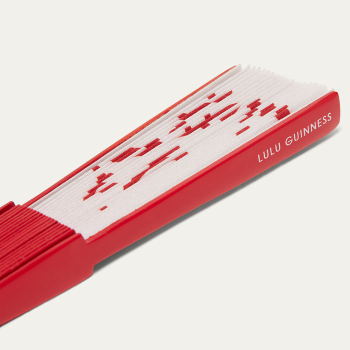 Close-up image of a red and white fan with 'Lulu Guinness' branding on a light gray background