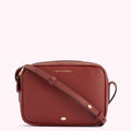 A burnt orange Lulu Guinness crossbody bag.
