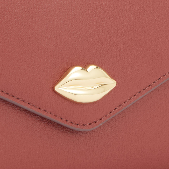 Close-up of a dusty rose leather purse with a gold lip-shaped accent.