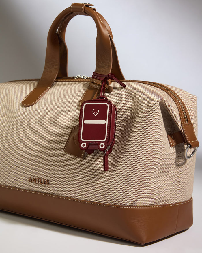a brown and tan bag with a red luggage tag