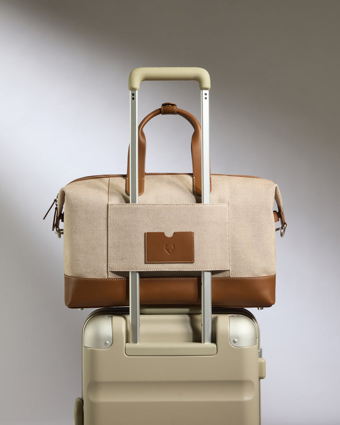 a brown and tan bag on top of a suitcase