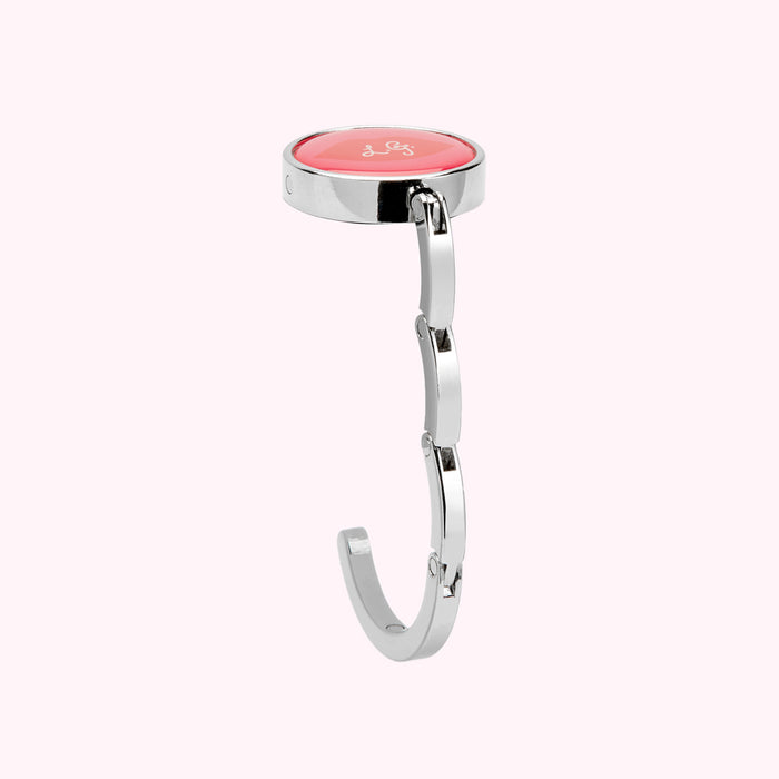 Silver handbag hook with coral-coloured circular top.