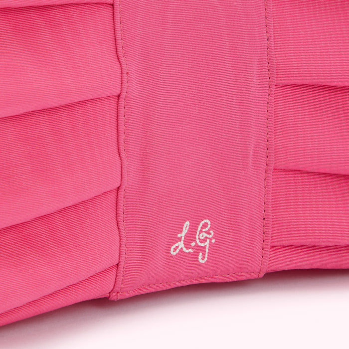 Close-up of a hot pink pleated fabric bag with a subtle embossed logo.