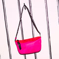 Hot pink nylon shoulder bag with a branded 'Lulu Guinness' strap handing on a hook.