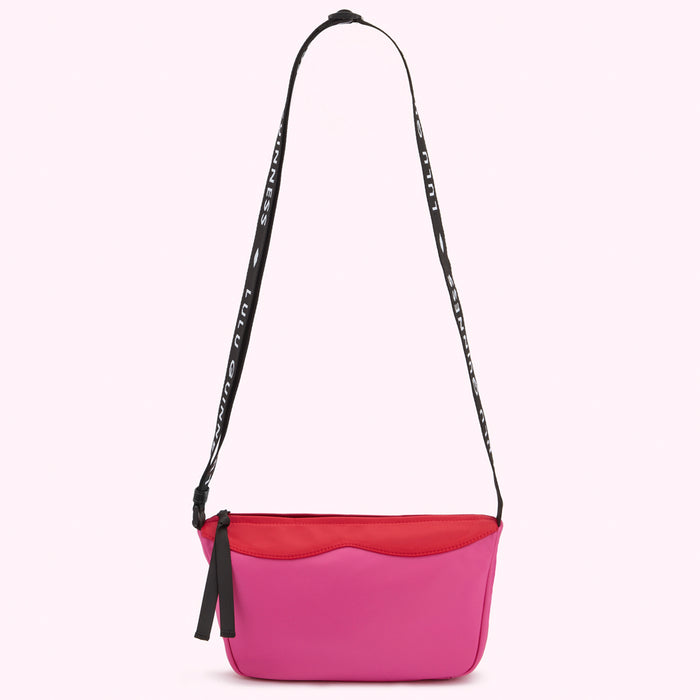 Bright pink, red and black Lulu Guinness nylon crossbody bag with a black shoulder strap that says "Lulu Guinness."