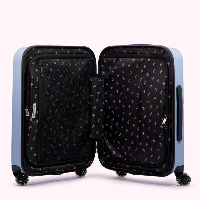 Open light blue suitcase with black interior lining and small zippered pockets.