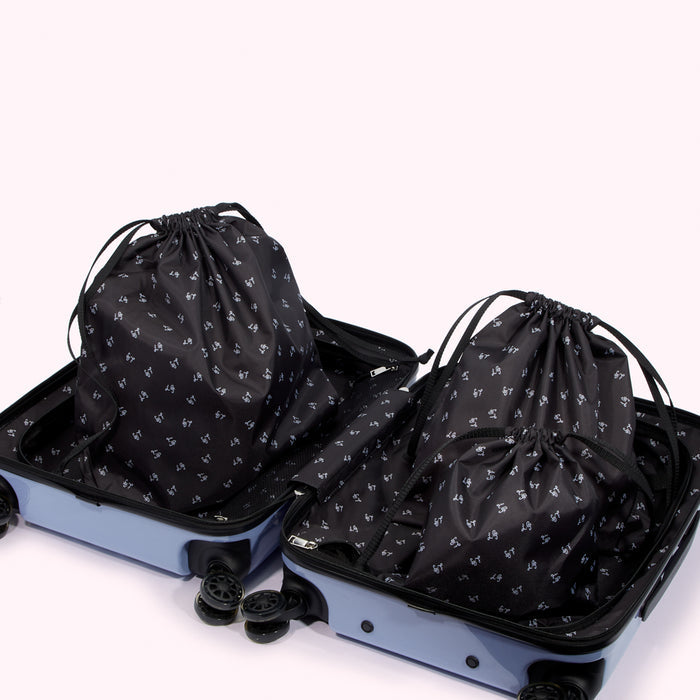 Two light blue suitcases open to reveal several black drawstring bags with a repeating pattern. The background is white.