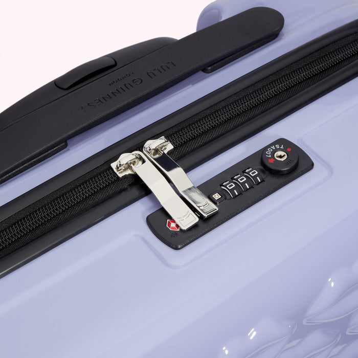 Close-up of a lavender Lulu Guinness suitcase showing the TSA-approved combination lock and zipper.