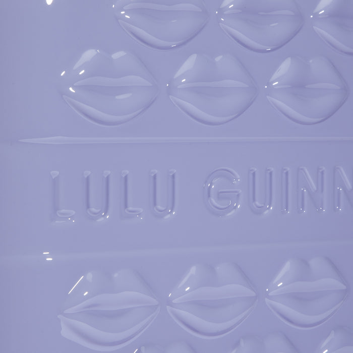 Close-up of a lavender-coloured Lulu Guinness item featuring embossed lips and the brand's logo.